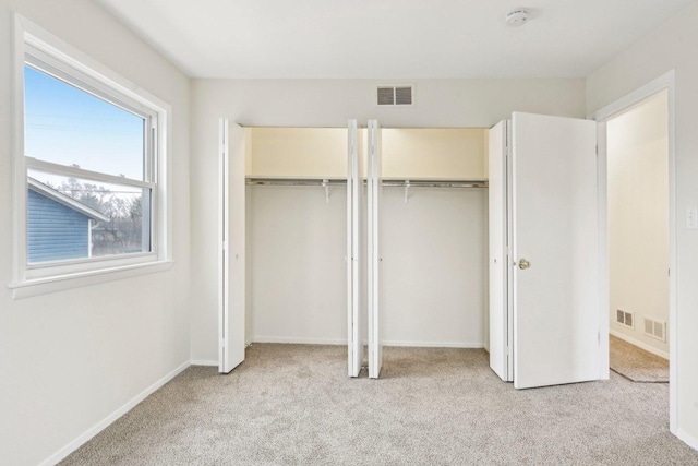 unfurnished bedroom with multiple closets and light carpet