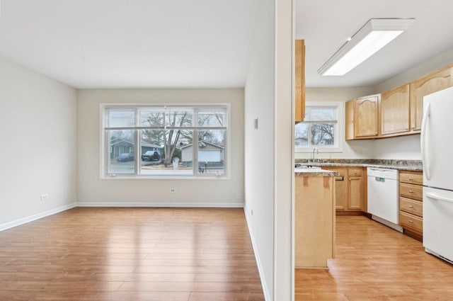 kitchen featuring white appliances, light wood-type flooring, a healthy amount of sunlight, and light brown cabinets