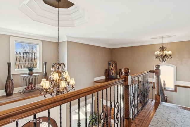 corridor featuring baseboards, ornamental molding, wood finished floors, an upstairs landing, and a notable chandelier