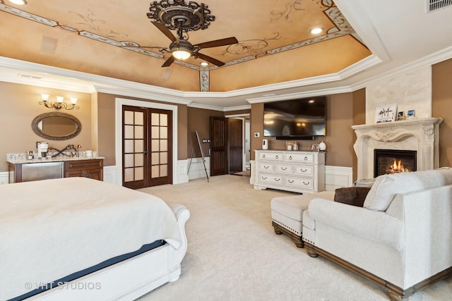 bedroom featuring light carpet, a tray ceiling, ornamental molding, and french doors