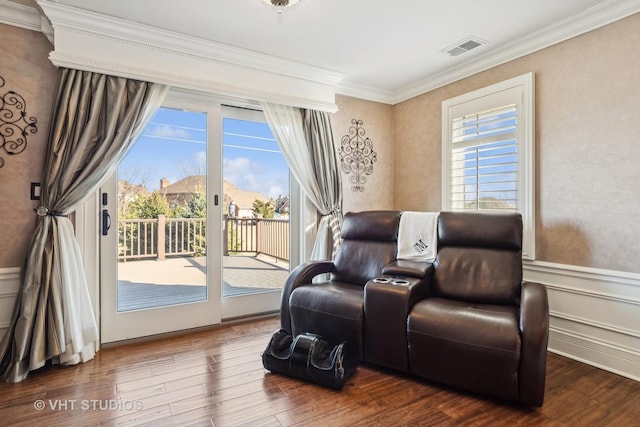 living area featuring wainscoting, visible vents, crown molding, and wood finished floors