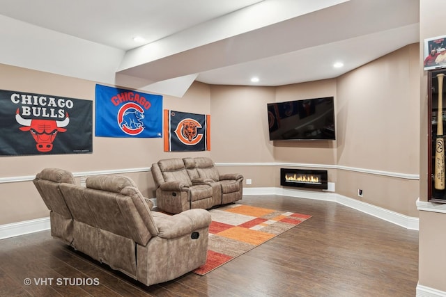 living area with recessed lighting, baseboards, wood finished floors, and a glass covered fireplace