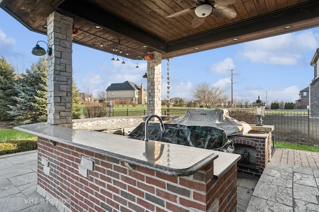 view of patio featuring outdoor dry bar, fence, and a ceiling fan