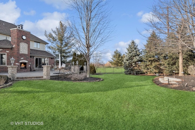 view of yard featuring a patio area, a brick fireplace, and fence