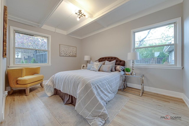 bedroom with light hardwood / wood-style floors, multiple windows, and vaulted ceiling with beams