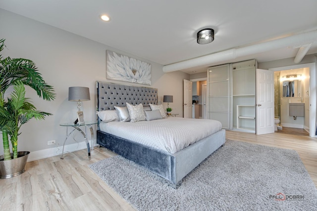 bedroom with ensuite bathroom and light wood-type flooring