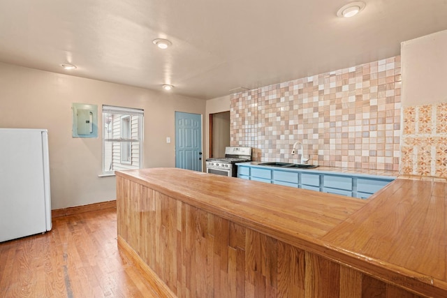 kitchen featuring wood counters, sink, gas stove, tasteful backsplash, and white fridge