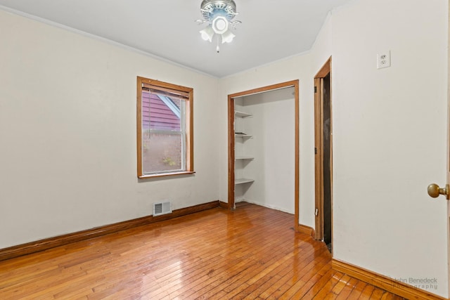 unfurnished bedroom with crown molding, a closet, and light hardwood / wood-style flooring