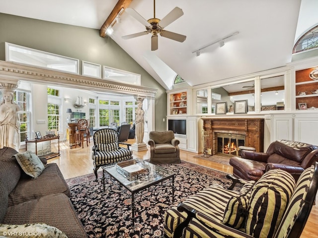 living room with high vaulted ceiling, rail lighting, ceiling fan, beam ceiling, and light hardwood / wood-style flooring
