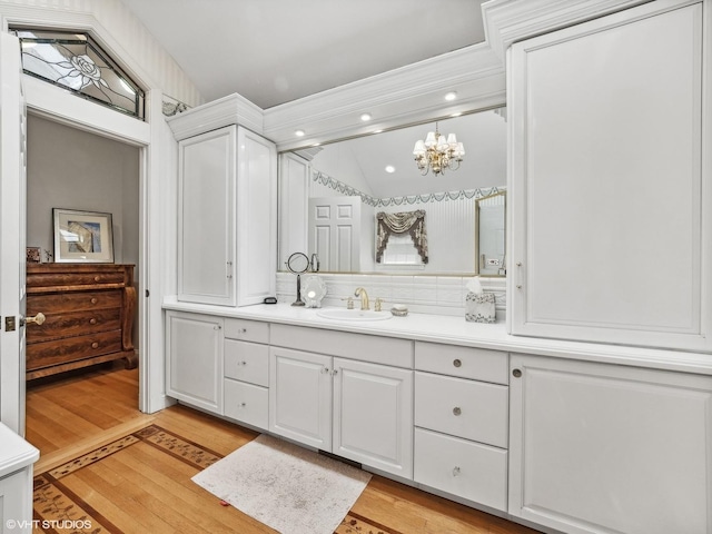 bathroom with vanity, a notable chandelier, wood-type flooring, and vaulted ceiling