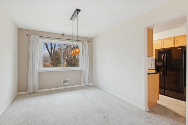 unfurnished dining area featuring light carpet