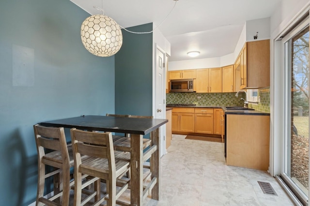 kitchen featuring sink, backsplash, light brown cabinetry, and black gas cooktop