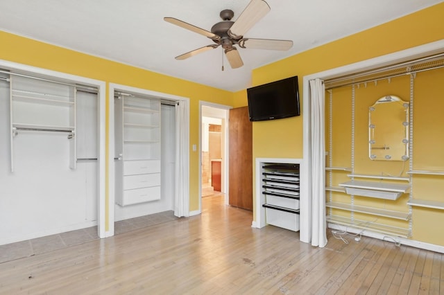 unfurnished bedroom featuring multiple closets, ceiling fan, and light hardwood / wood-style floors