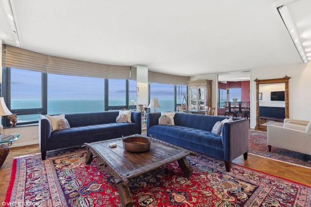 living room featuring a water view, parquet floors, and a wealth of natural light