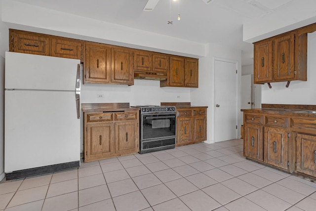 kitchen with white refrigerator, black stove, and light tile patterned floors