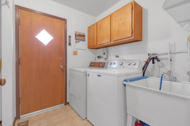 clothes washing area featuring sink, washer and clothes dryer, and cabinets