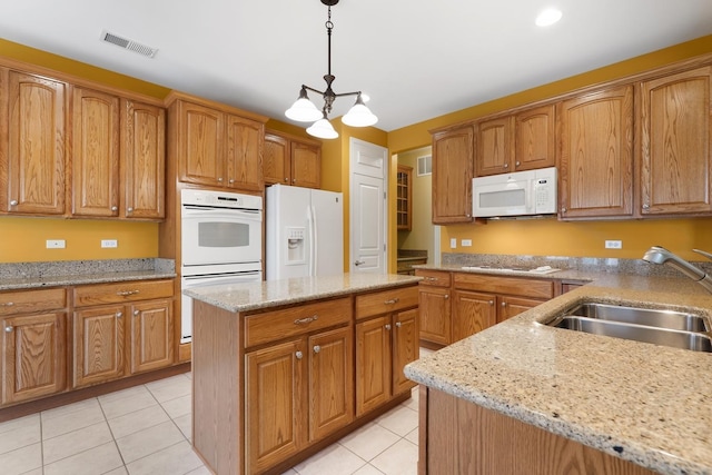 kitchen featuring sink, white appliances, light tile patterned floors, hanging light fixtures, and a center island