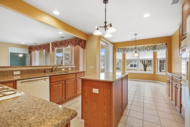 kitchen with a center island, sink, white dishwasher, and decorative light fixtures