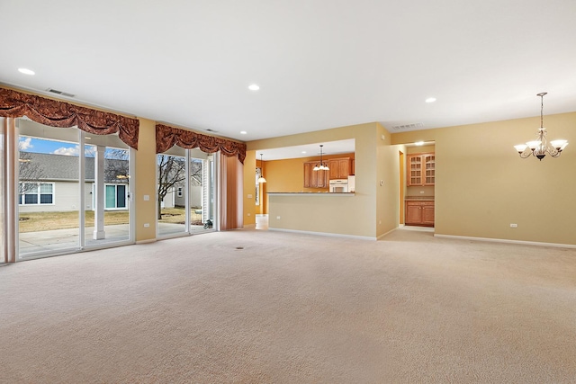 unfurnished living room with an inviting chandelier and light colored carpet