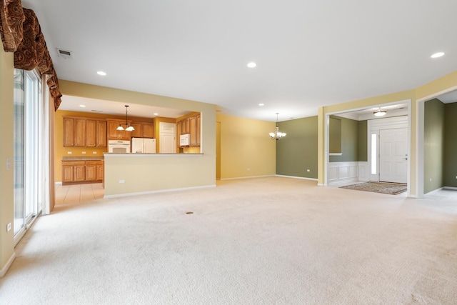 unfurnished living room featuring a notable chandelier and light colored carpet