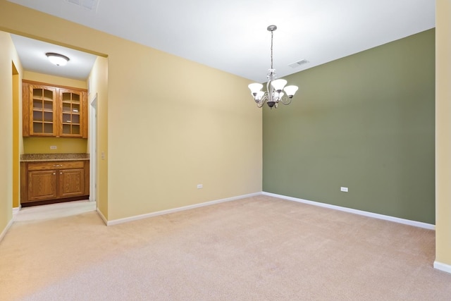 carpeted spare room featuring an inviting chandelier