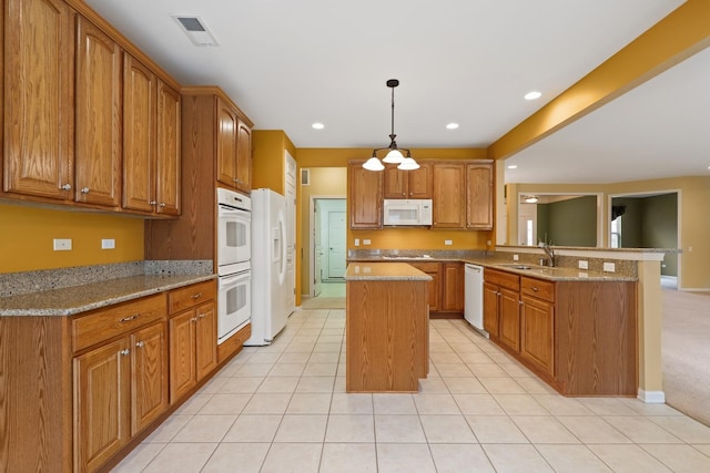 kitchen featuring sink, a center island, kitchen peninsula, white appliances, and light stone countertops