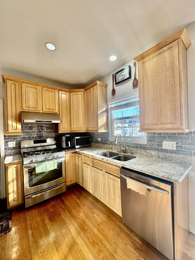 kitchen with sink, appliances with stainless steel finishes, backsplash, light brown cabinets, and light wood-type flooring