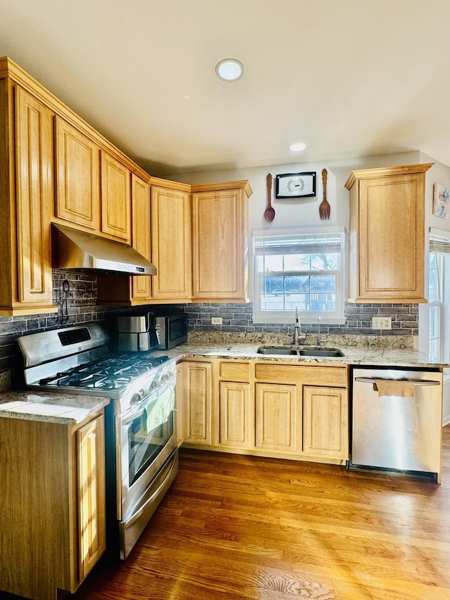 kitchen with sink, backsplash, stainless steel appliances, light brown cabinets, and light wood-type flooring