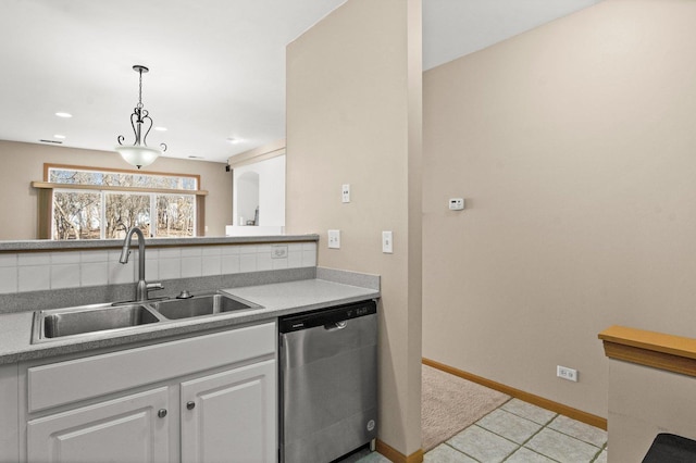 kitchen featuring sink, white cabinetry, light tile patterned floors, stainless steel dishwasher, and pendant lighting