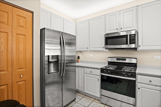 kitchen with stainless steel appliances, white cabinetry, and light tile patterned floors