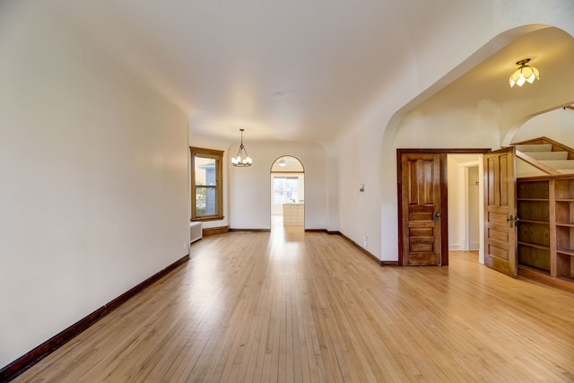 empty room featuring an inviting chandelier and light wood-type flooring