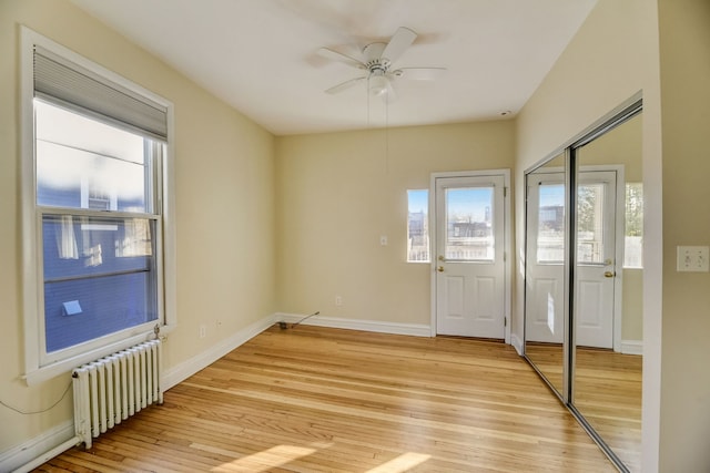 interior space featuring a wealth of natural light, radiator heating unit, and light wood-type flooring