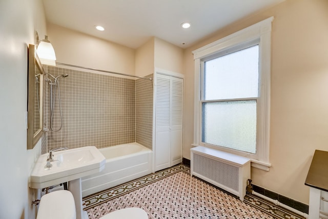 bathroom featuring tiled shower / bath, radiator heating unit, and toilet