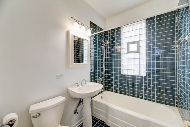 bathroom featuring plenty of natural light, toilet, and tiled shower / bath