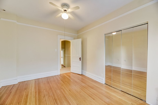 unfurnished bedroom with wood-type flooring, crown molding, ceiling fan, and a closet