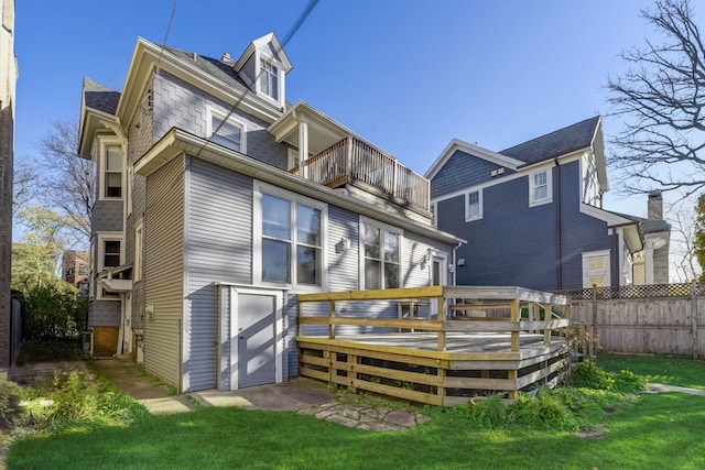 back of property featuring a balcony, a yard, and a deck