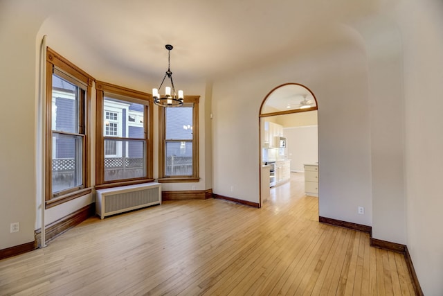 unfurnished room with radiator, an inviting chandelier, and light wood-type flooring