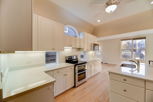 kitchen featuring appliances with stainless steel finishes, sink, backsplash, and light wood-type flooring