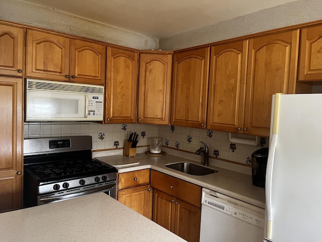 kitchen with tasteful backsplash, white appliances, and sink