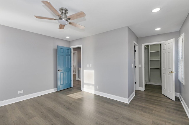 unfurnished bedroom with dark hardwood / wood-style floors, ceiling fan, and a spacious closet