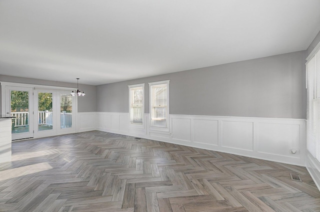 empty room with parquet flooring and a notable chandelier