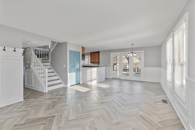 unfurnished living room featuring a chandelier and light parquet floors