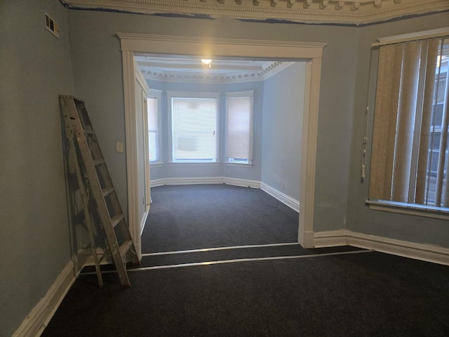 spare room featuring dark colored carpet and ornamental molding