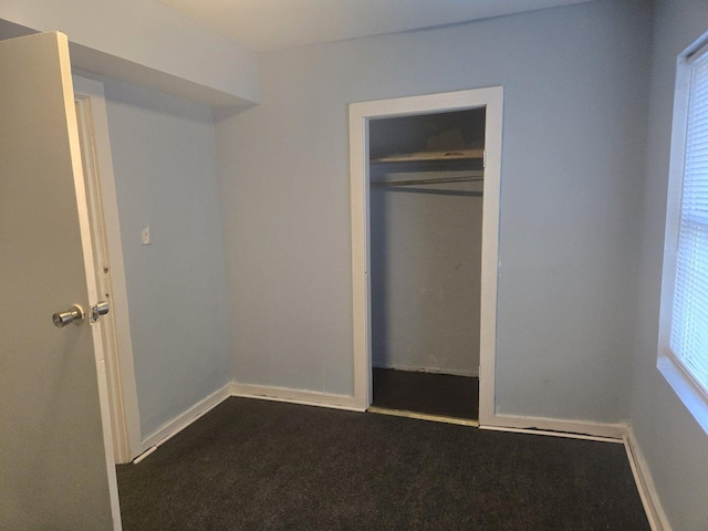 unfurnished bedroom with a closet and dark colored carpet