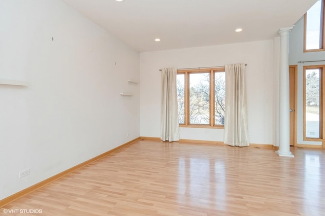 unfurnished room with decorative columns and light wood-type flooring