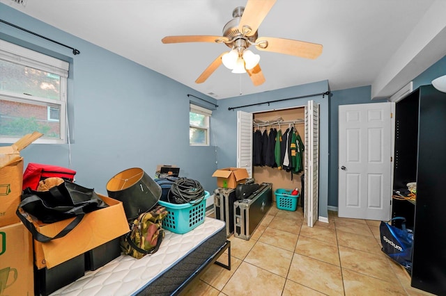 tiled bedroom with ceiling fan and a closet