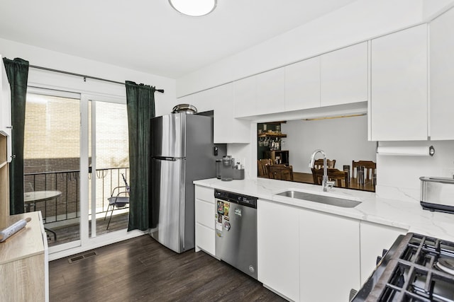 kitchen with dark wood-type flooring, sink, light stone counters, white cabinetry, and stainless steel appliances