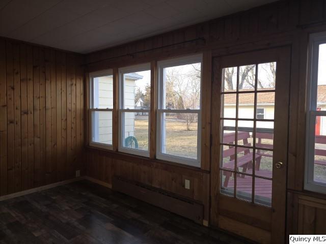 interior space featuring a baseboard radiator, dark hardwood / wood-style floors, and wood walls