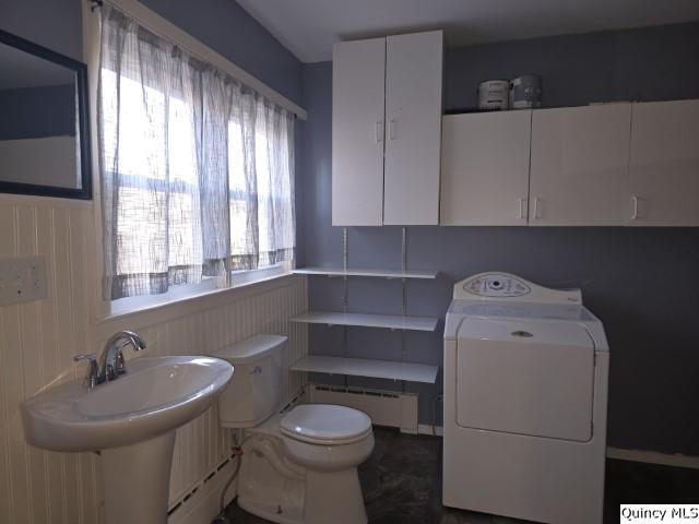 bathroom featuring washer / dryer, a healthy amount of sunlight, baseboard heating, and toilet