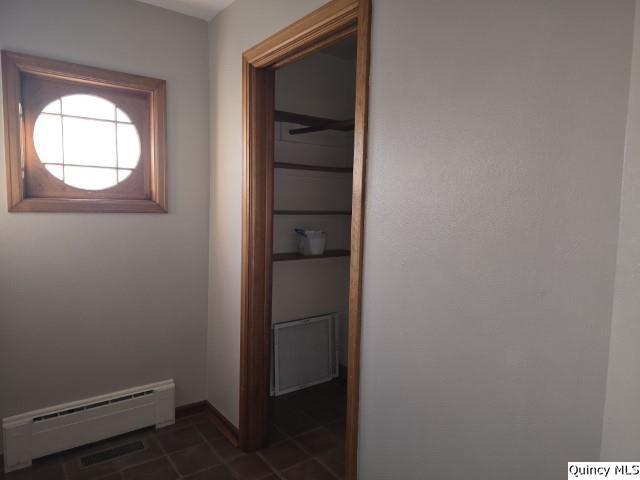 corridor featuring a baseboard radiator and dark tile patterned floors